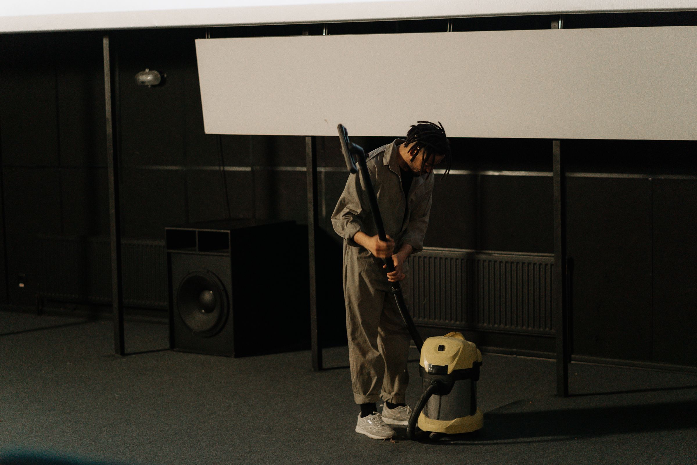 Uniformed worker vacuuming a commercial auditorium floor