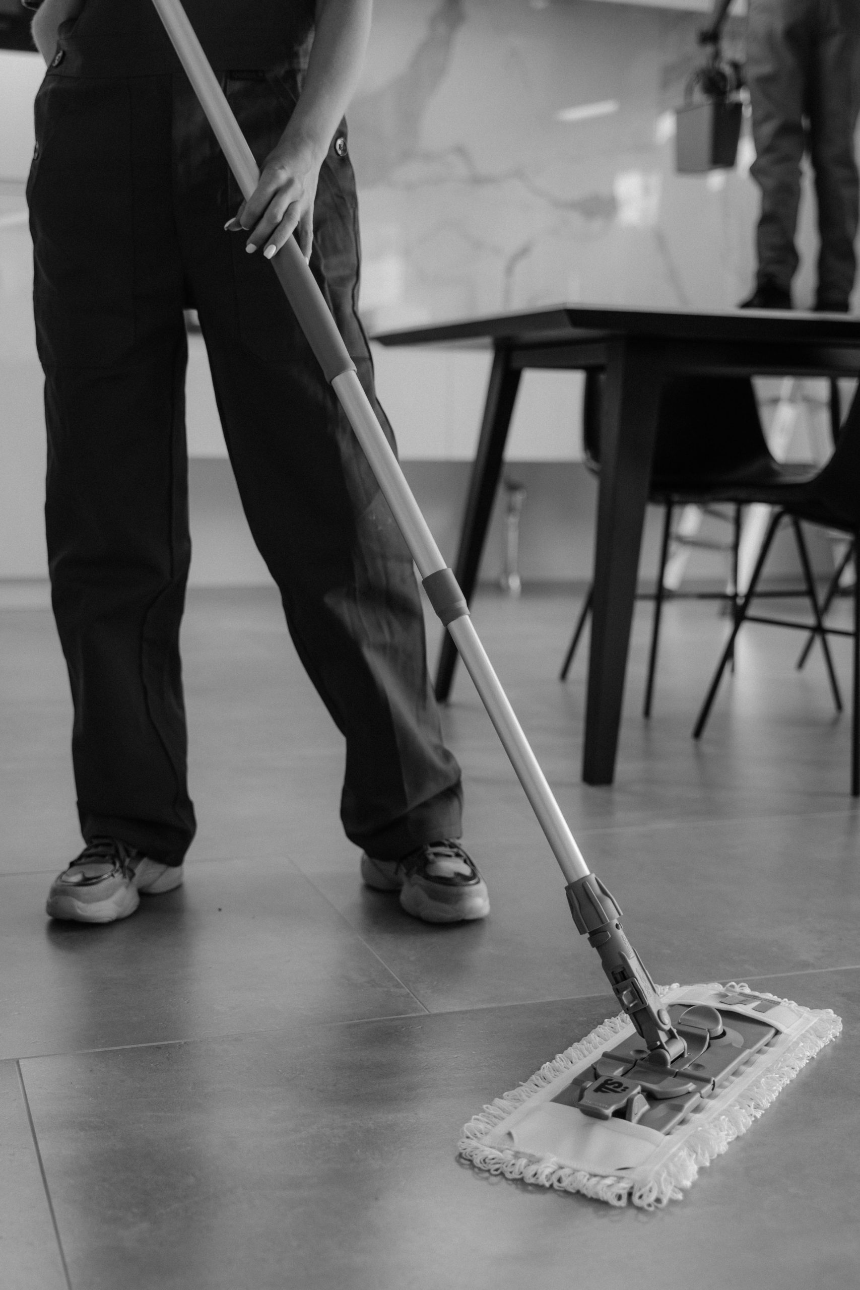 Person cleaning a tiled floor for commercial floor maintenance planning